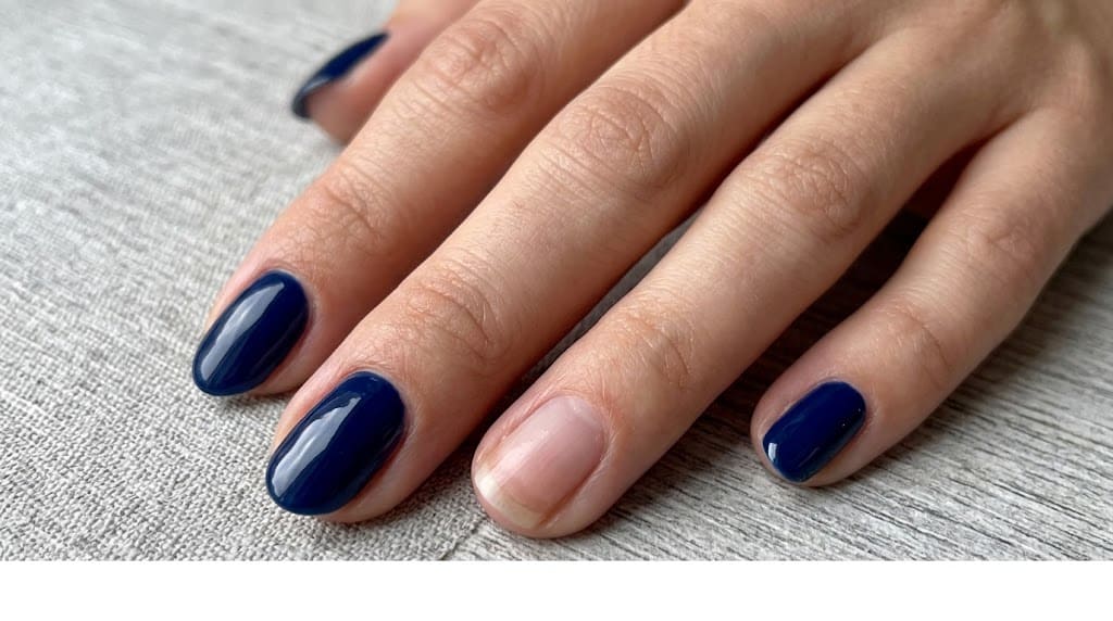 Deep navy blue nails with one bare ring finger for a modern minimalist patriotic nail style.