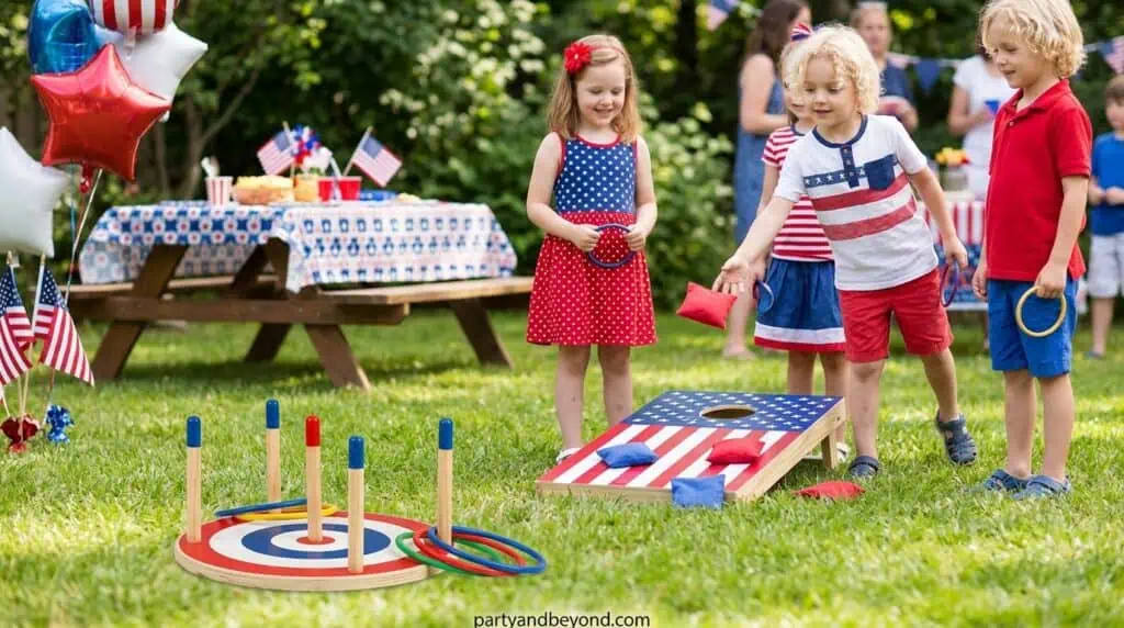 Kids playing ring toss game at patriotic outdoor party.