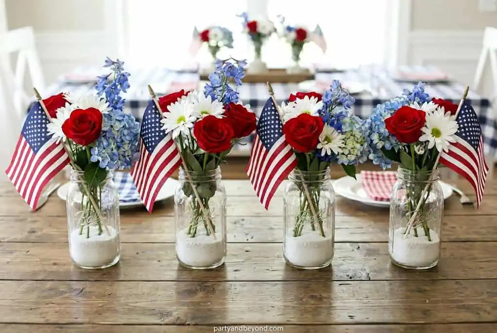 Mason jar centerpieces with small American flags and fresh flowers