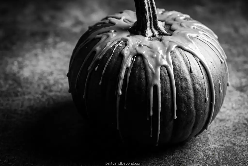 Black pumpkin with white dripping paint creating candle wax effect