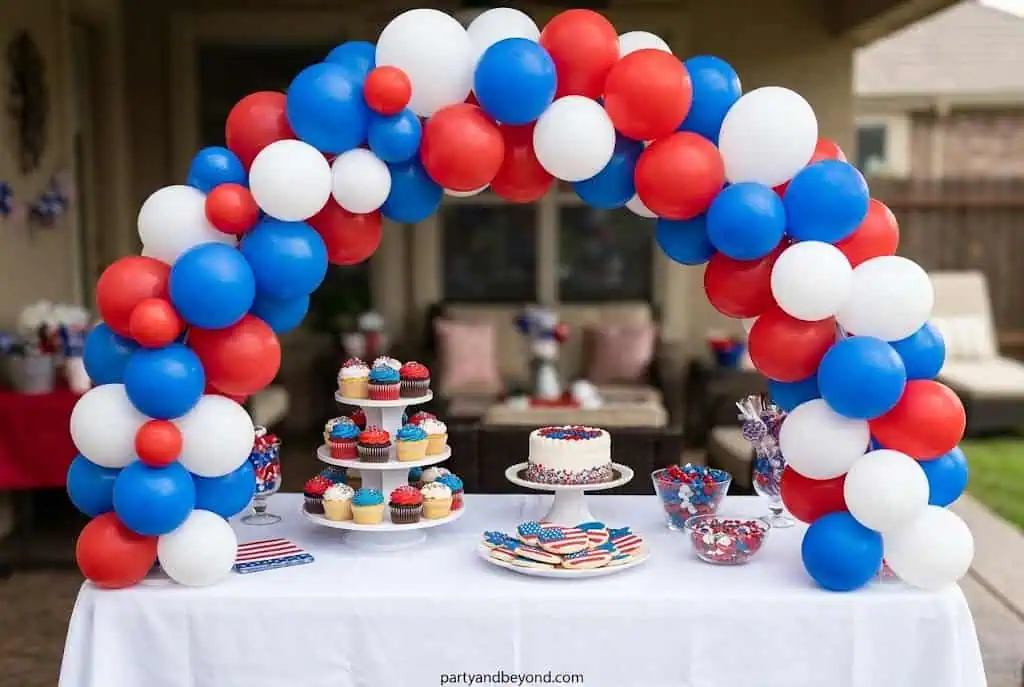 DIY patriotic balloon arch with red white and blue balloons over dessert table
