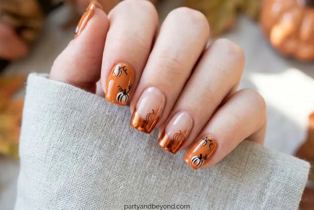 Rose gold chrome French tip nails with minimalist pumpkin detail.