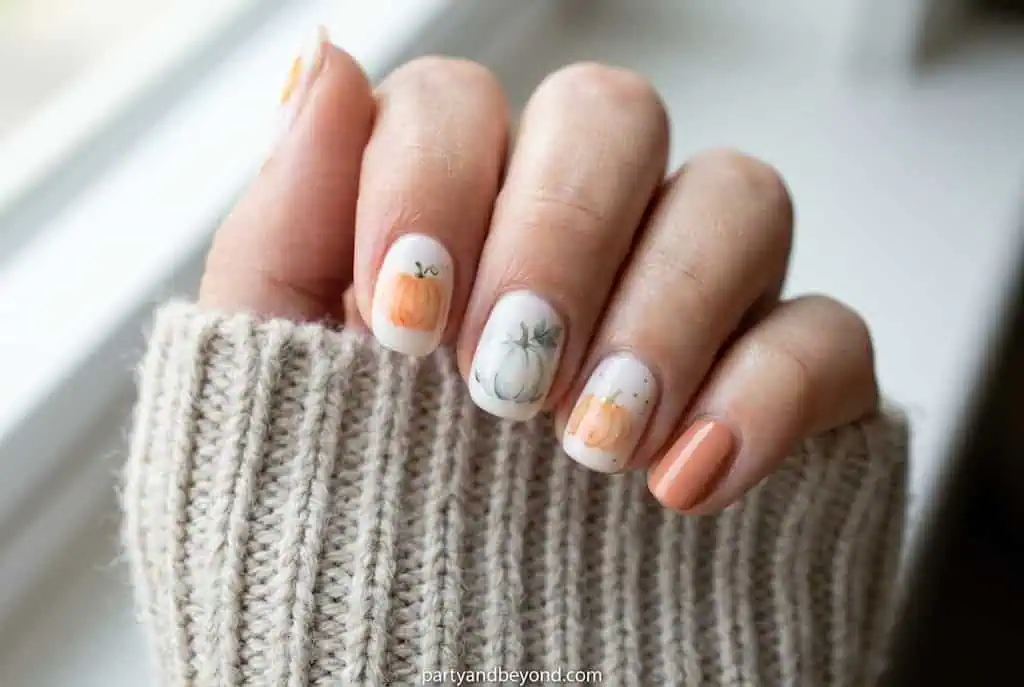Soft watercolor pumpkin nail art with blended orange and amber tones.