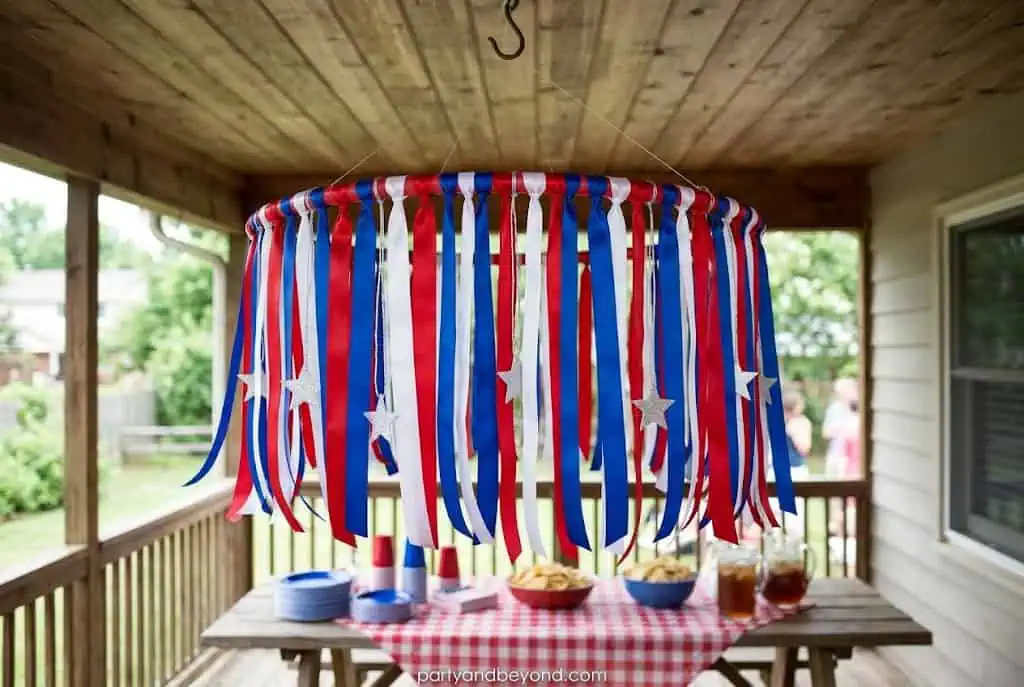 DIY patriotic ribbon chandelier hanging above a 4th of July food table