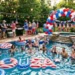The Ultimate Guide to Hosting a 4th of July Pool Party (Food, Games & Decor) Festive 4th of July pool party with guests enjoying swimming, patriotic decorations, and American fl.