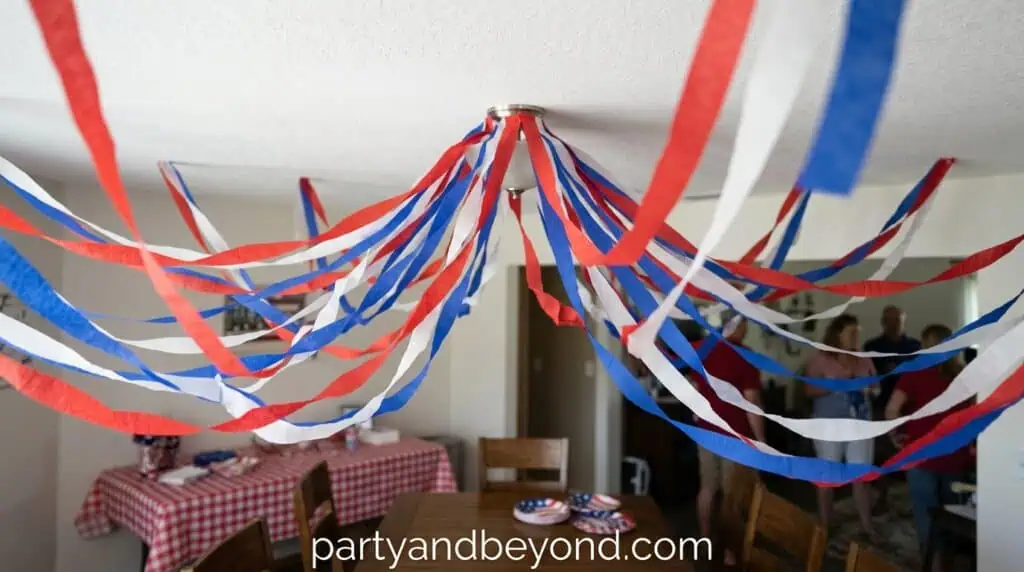 Red, white, and blue streamers hanging from a covered patio ceiling for party decoration.
