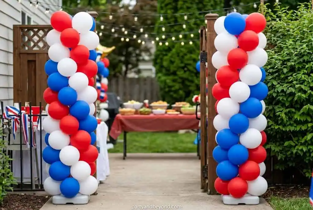 Red white and blue balloon column stands framing a 4th of July party table