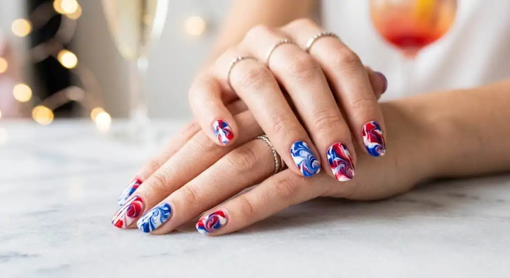 Swirled marble nail art combining red, white, and blue colors for a creative festive look.