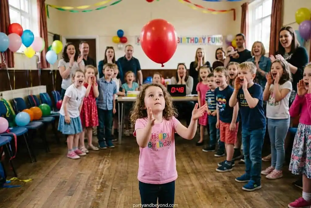 Young child keeping a colorful balloon in the air during a birthday party activity