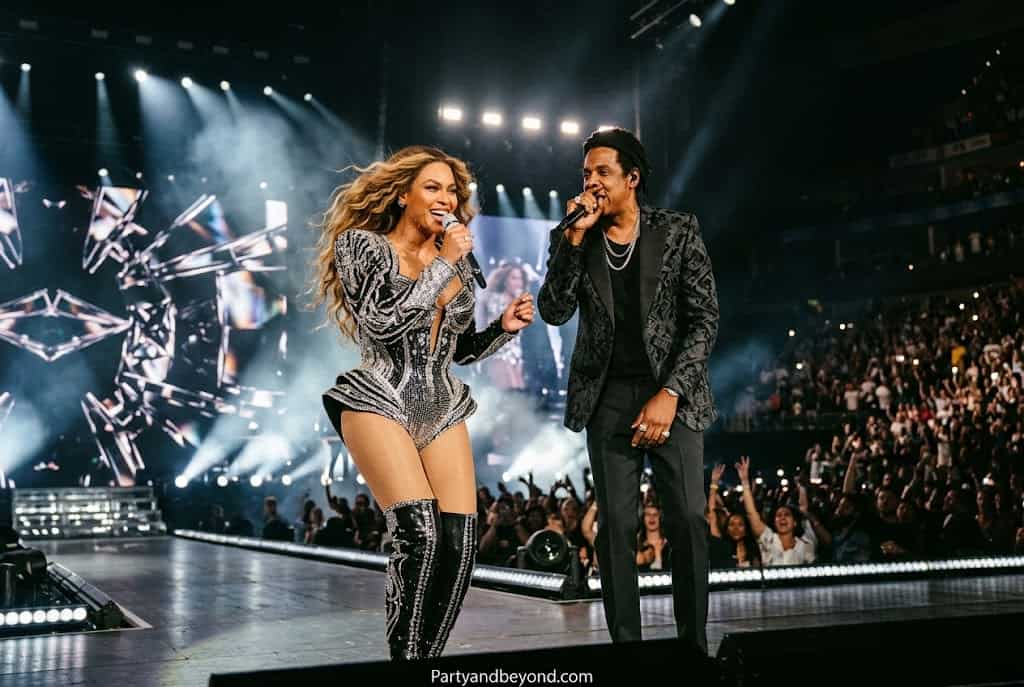 Black couple dressed as Beyoncé and Jay-Z in silver Renaissance-inspired Halloween costumes.