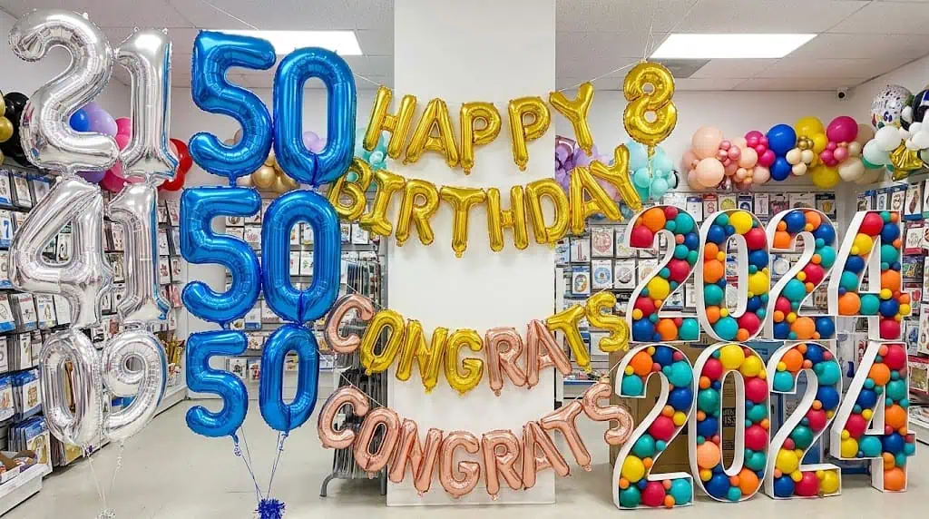 “Large gold foil balloon numbers and letters used as party backdrop décor”