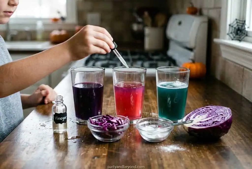 Three vibrant homemade fruit juices in glasses with ingredients on a kitchen counter.
