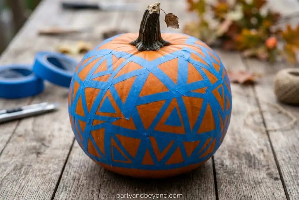 Pumpkin with geometric triangle shapes in teal and cream separated by tape lines