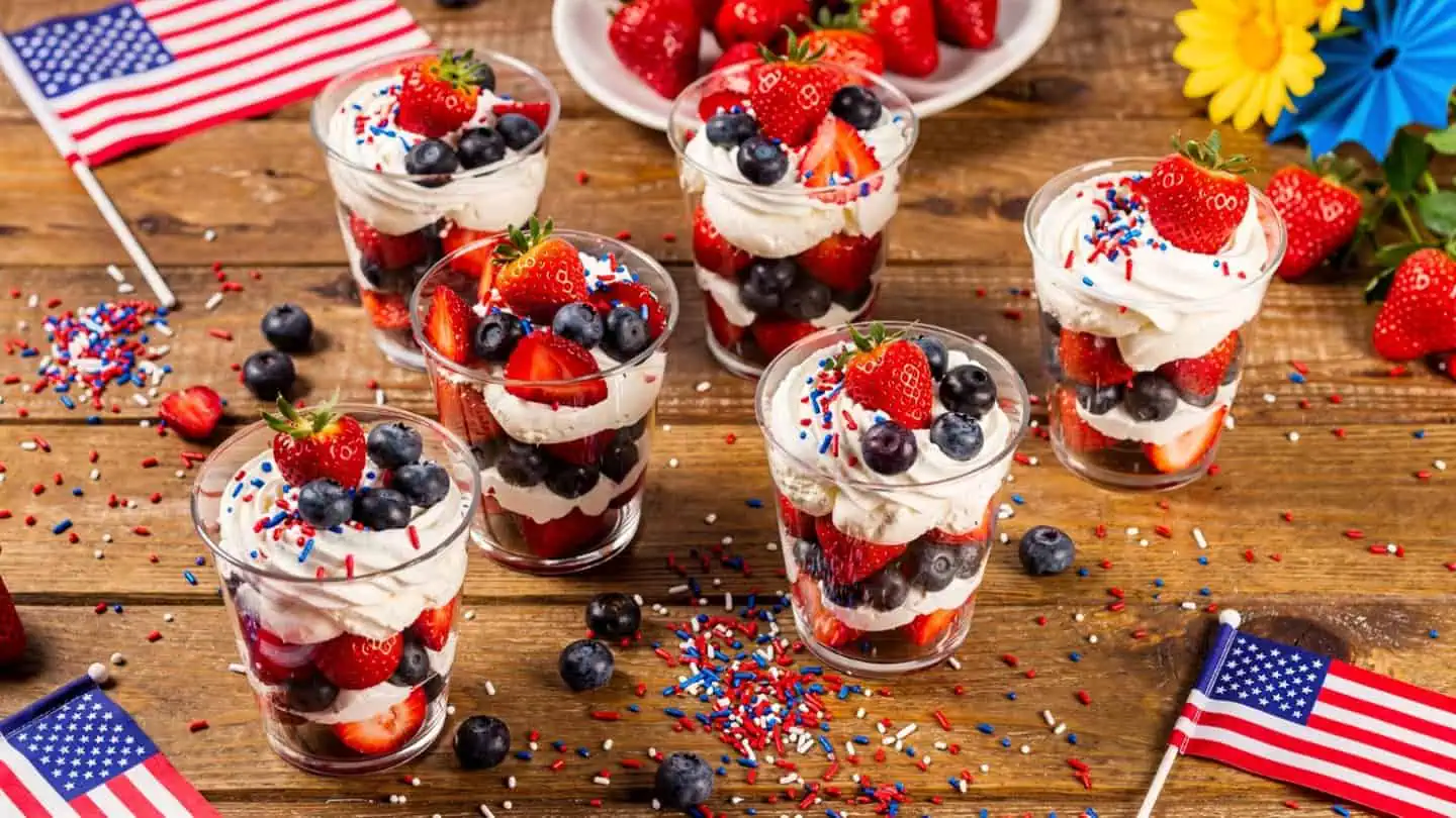 Easy 4th of July no-bake desserts spread on a patriotic table with watermelon flag cake, Oreo pops, fruit skewers, and Jello cups