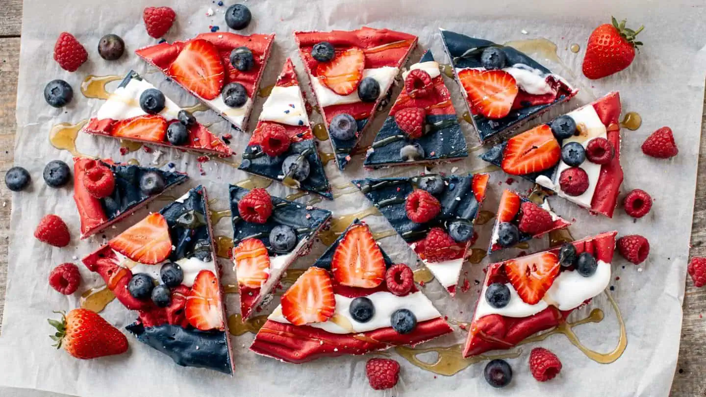 Frozen yogurt bark with strawberries, blueberries, and honey broken into pieces for healthy patriotic summer dessert Easy 4th of July Desserts