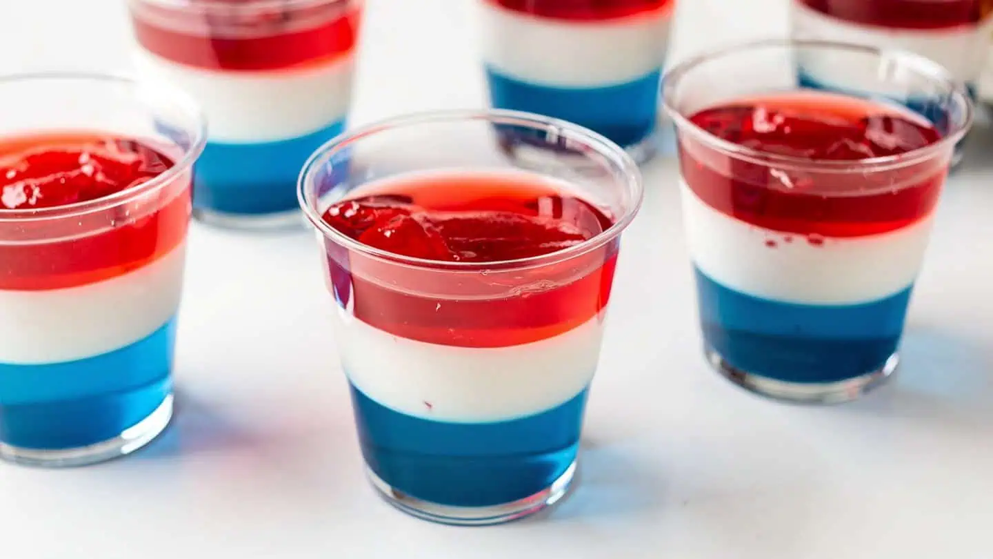 Red white and blue layered Jello parfait cups in clear glasses for easy 4th of July no-bake dessert
