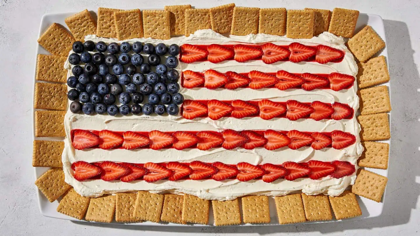 Cream cheese dessert dip decorated like an American flag with strawberry stripes and blueberry corner served with graham crackers Easy 4th of July Desserts