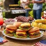 The Ultimate 4th of July BBQ Menu: 25 Crowd-Pleasing Recipes for Your Cookout (2026) Festive outdoor party with burgers, corn, desserts, and patriotic decorations.