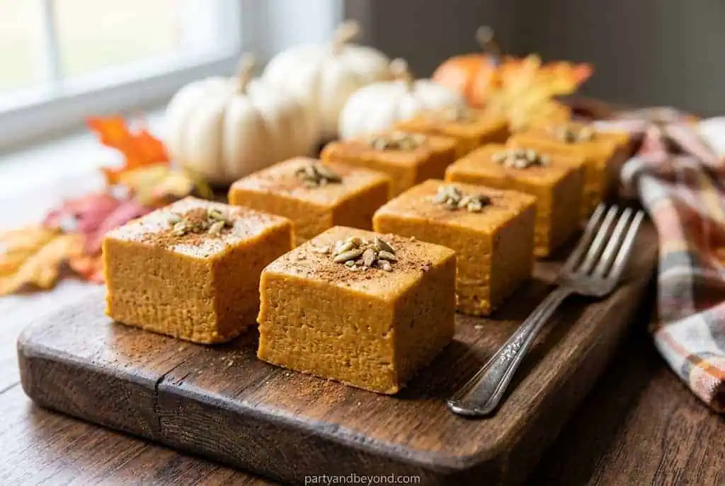 Pumpkin bars with pumpkin seeds on a wooden serving board for Halloween.
