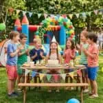 Summer Birthday Party Ideas for Kids (Outdoor Fun) Children celebrating birthday outdoors with balloons, cake, and party decorations.