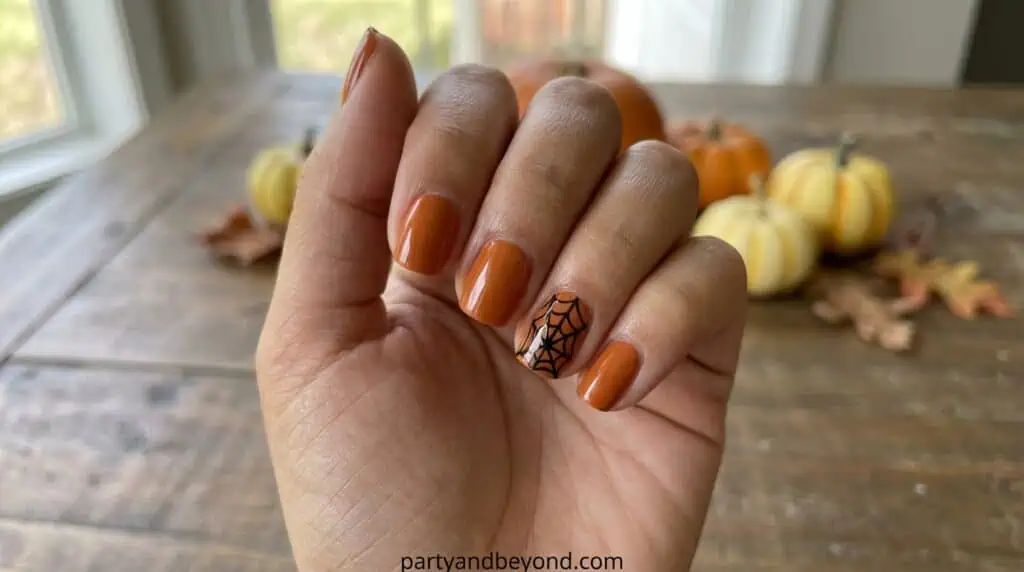 A single accent nail featuring a delicate spiderweb design drawn with thin lines. This is one of the easiest and most forgiving Halloween nail designs.