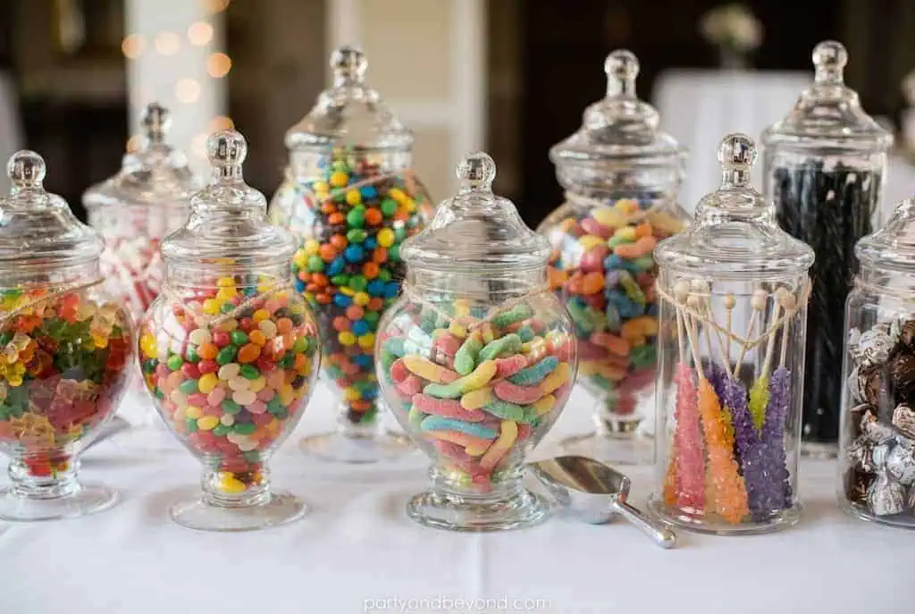 Glass jars filled with colorful Halloween candies on dessert table.