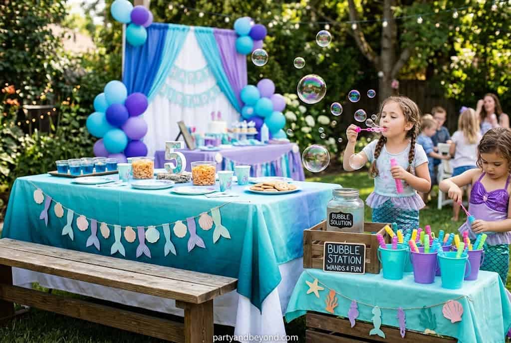 Outdoor bubble station with children blowing bubbles during a mermaid birthday party.
