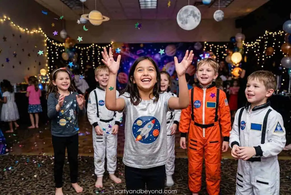 Kids keeping colorful balloons in the air during a fun space party game.