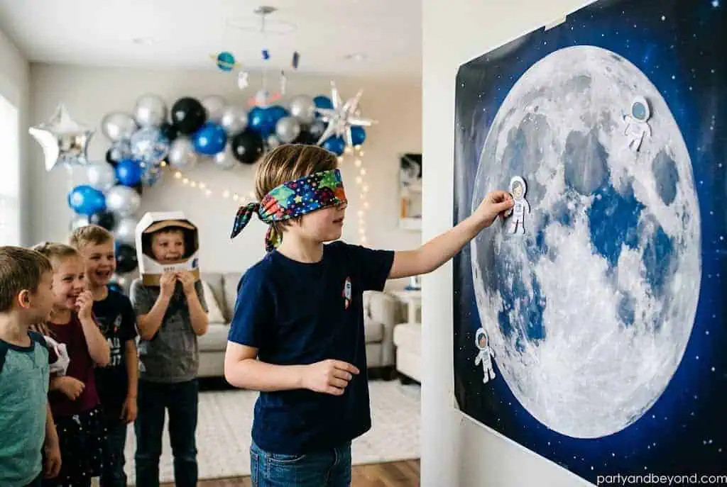 Space-themed version of pin the tail with an astronaut and moon poster.