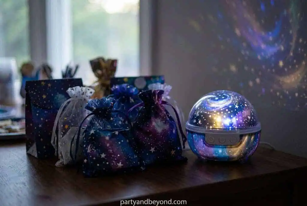 Star projector casting glowing constellations across the ceiling during a birthday party Space Birthday Party Ideas