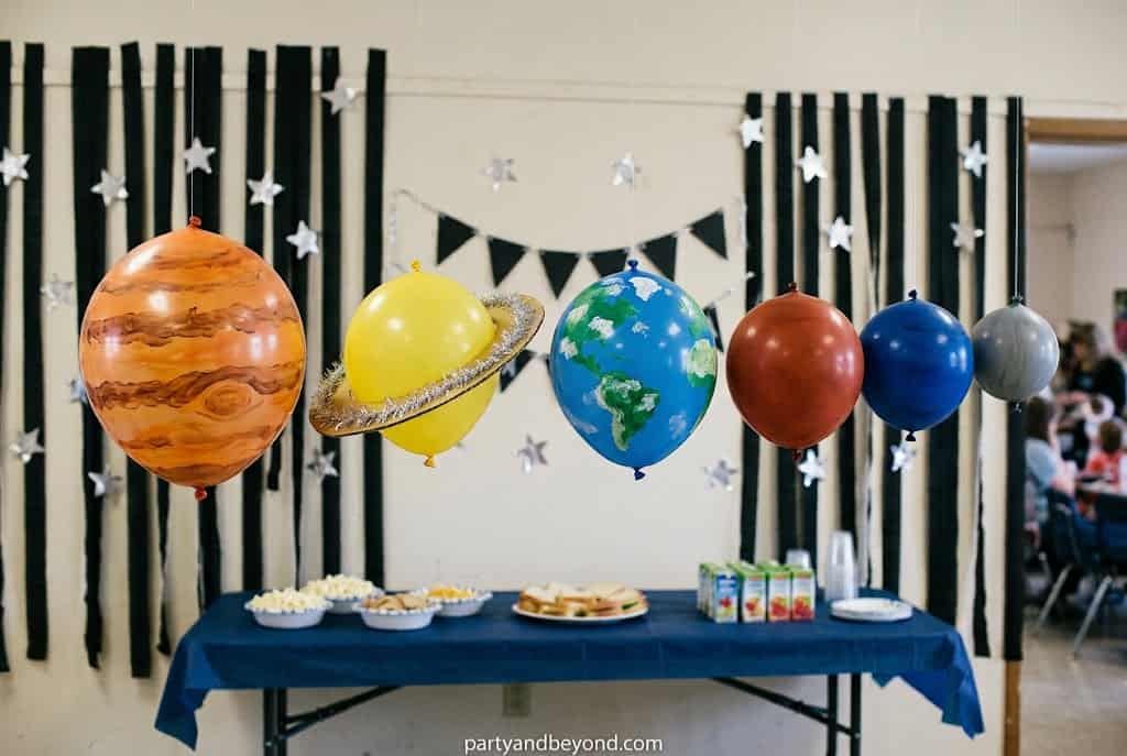 Colorful balloon planets hanging from the ceiling to resemble the solar system.