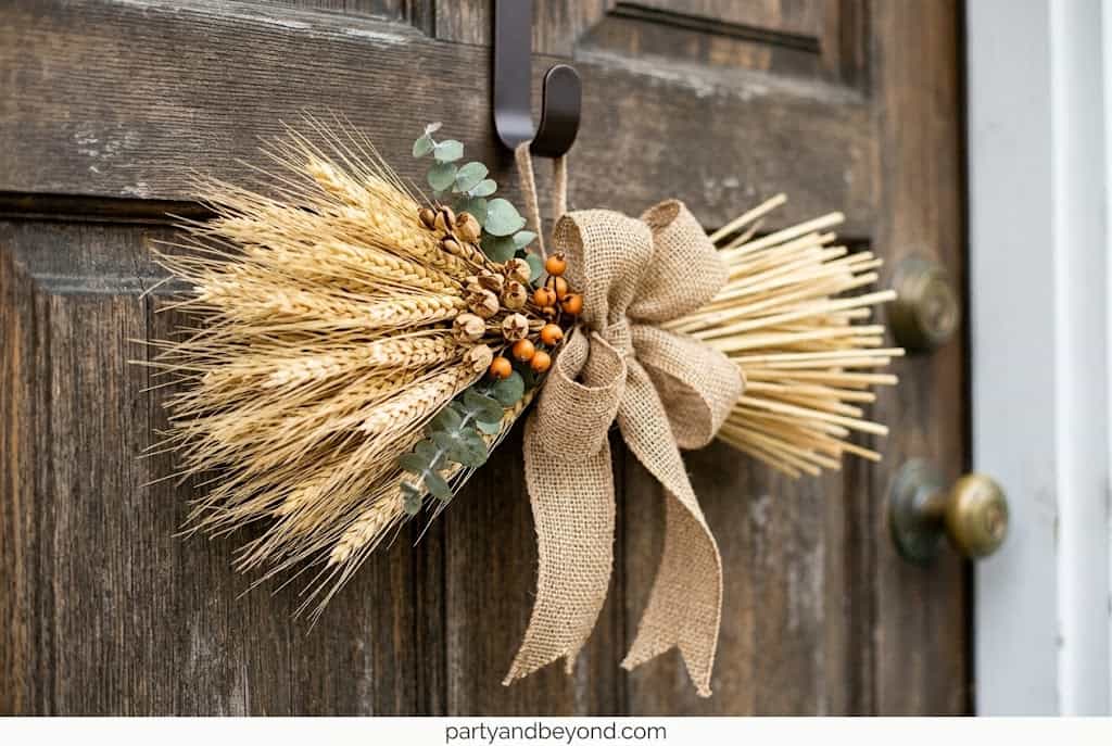 Dried wheat door swag tied with copper ribbon for rustic Thanksgiving entry decor.