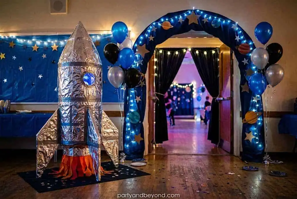 DIY foil-covered cardboard rocket entrance for a space-themed birthday party.