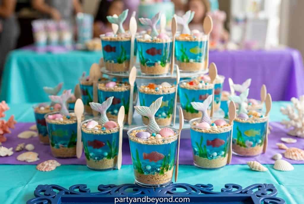 Blue jello cups with gummy fish creating a fun underwater dessert for kids.