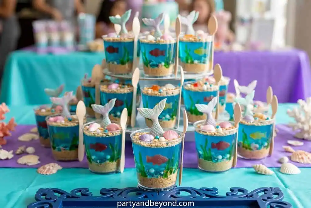 Blue jello cups with gummy fish creating a fun underwater dessert for kids.