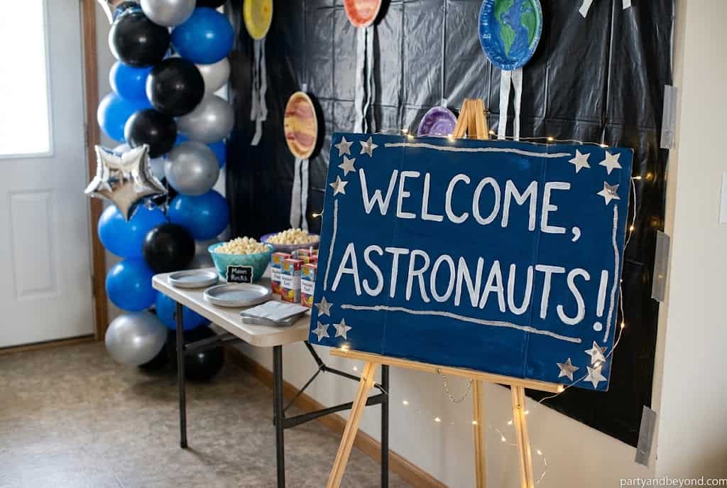 Personalized astronaut welcome sign greeting guests at a space birthday party.