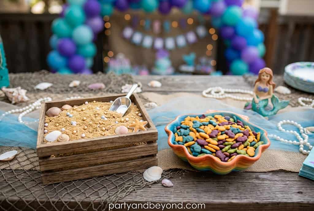 Fish-shaped crackers served with crushed graham cracker sand on an ocean-themed snack table.