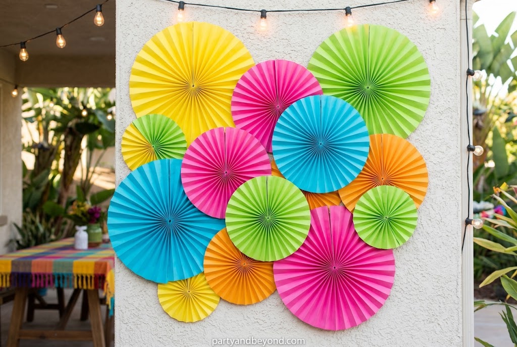 Colorful giant paper fans and pinwheels decorating an outdoor party wall