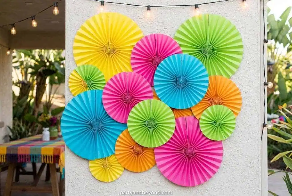 Colorful giant paper fans and pinwheels decorating an outdoor party wall