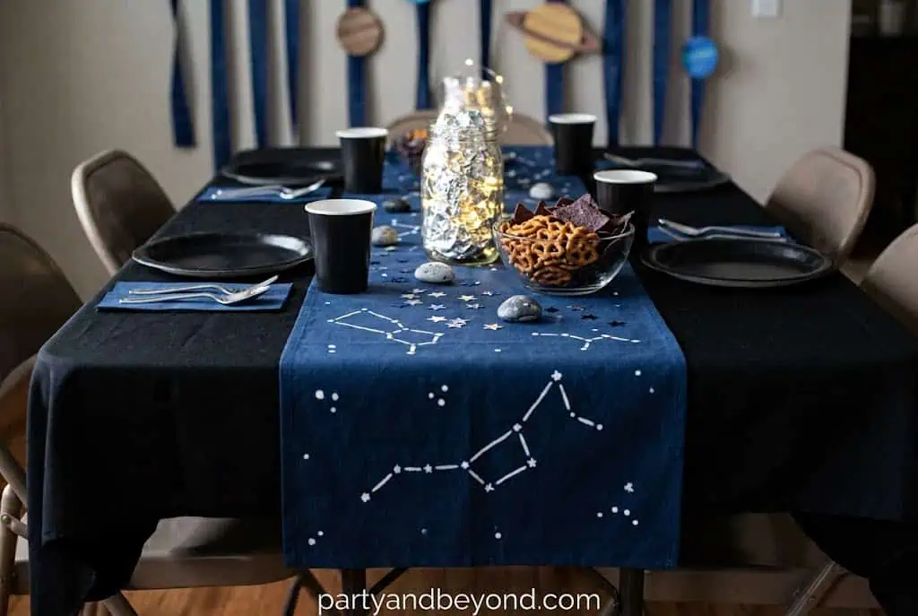 Black table runner decorated with silver star stickers forming constellation patterns.