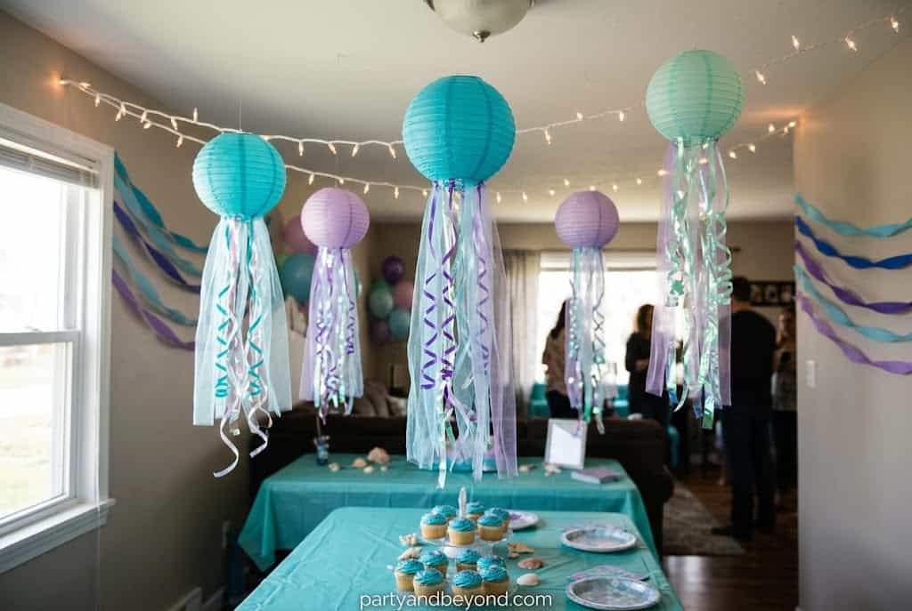 Paper lantern jellyfish with flowing ribbon tentacles hanging from the party ceiling.