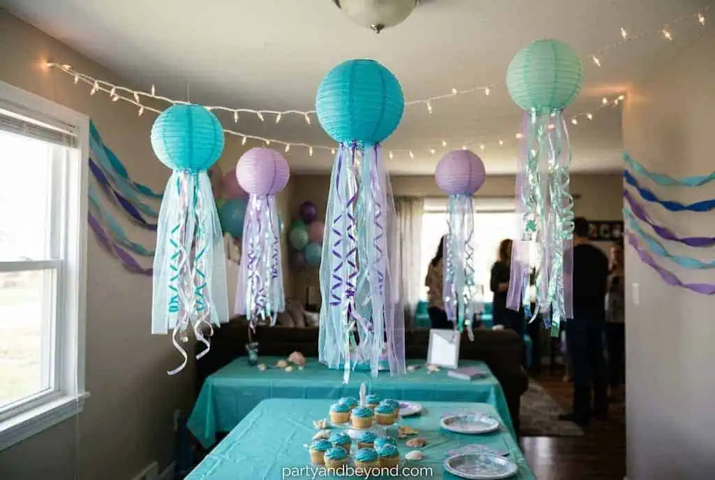 Paper lantern jellyfish with flowing ribbon tentacles hanging from the party ceiling.